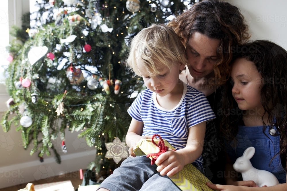 Two young kids opening presents on christmas with aunty - Australian Stock Image