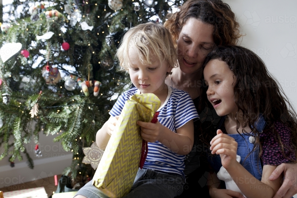 Two young kids opening presents on christmas with aunty - Australian Stock Image