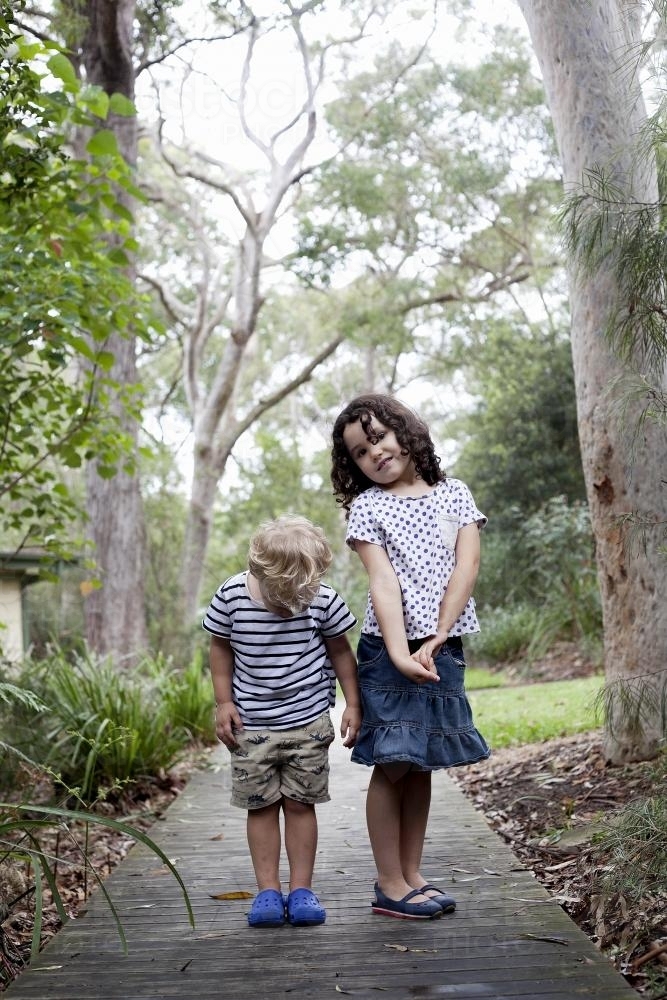 Two young kids standing on an outdoor wooden path - Australian Stock Image