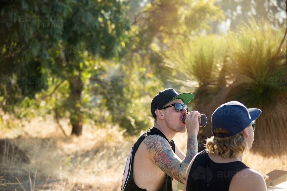 Two young men outdoors, drinking beer - Australian Stock Image