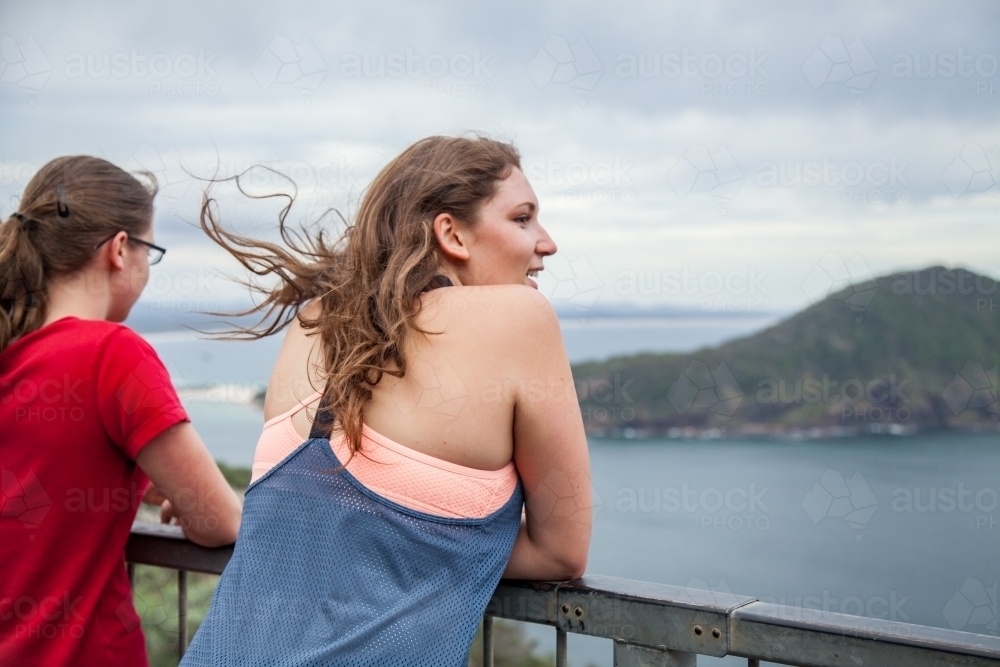 Two young people looking out to sea on a windy day by the ocean - Australian Stock Image