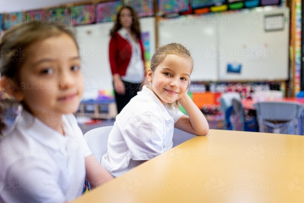 Two Young Schoolgirls sitting behind their desk smiling - Australian Stock Image