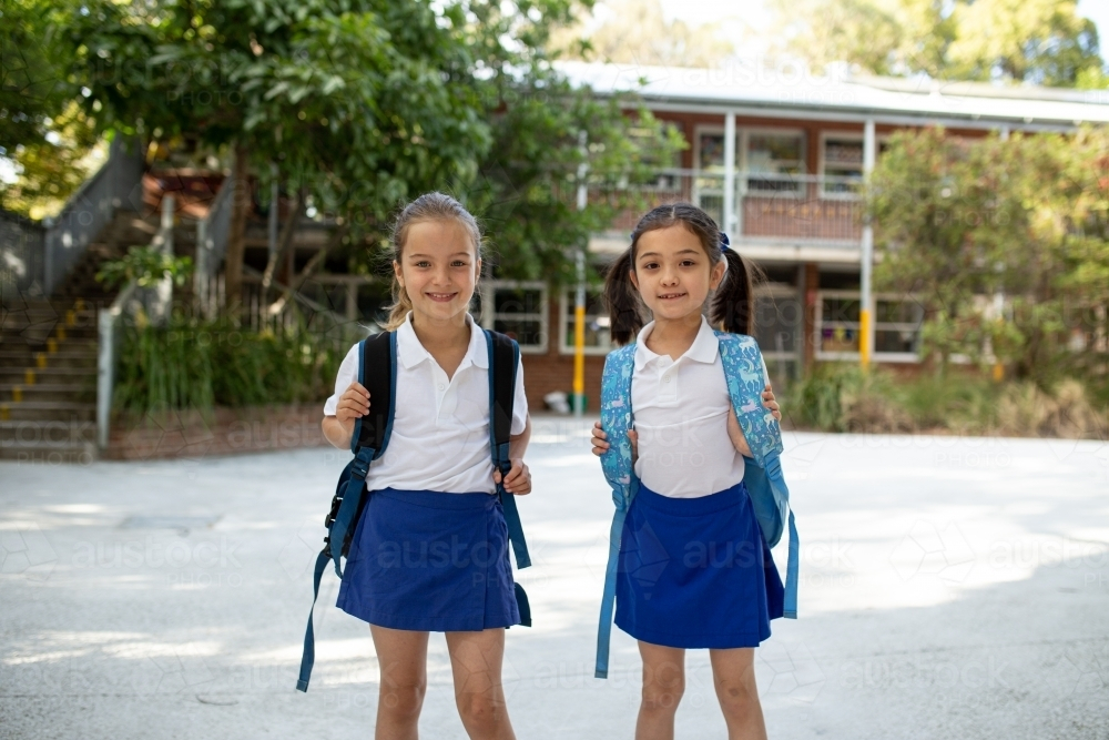 Image of Two young schoolgirls with their backpacks standing outside ...