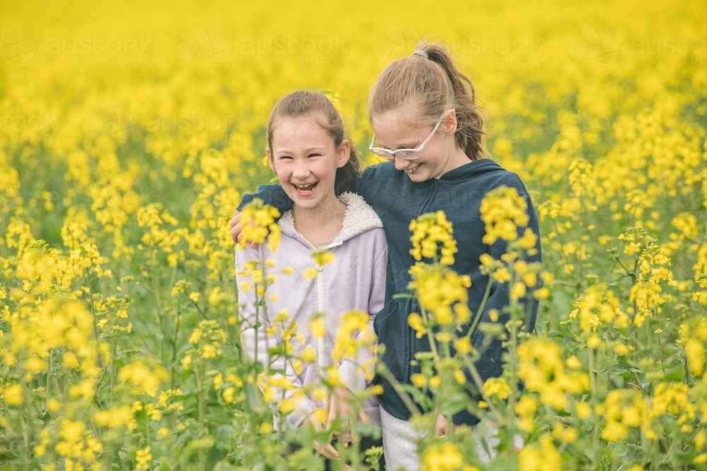 Two young sisters hanging out in their family canola field. - Australian Stock Image