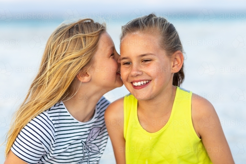 two young sisters sharing secrets and giggling - Australian Stock Image