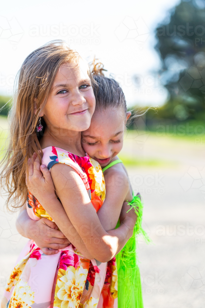 Two young Torres Strait Islander cousins hugging each other under the sun - Australian Stock Image