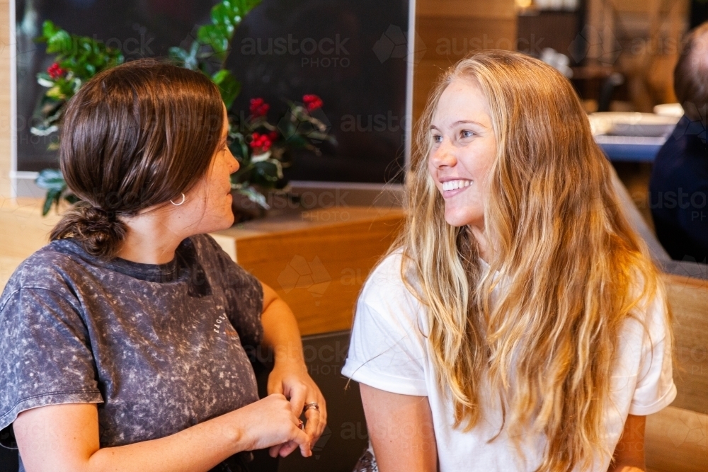 Two young women catching up and chatting in shopping mall - Australian Stock Image