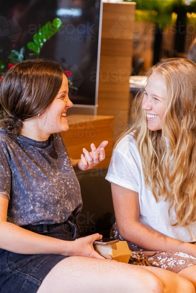 Two young women catching up and chatting in shopping mall - Australian Stock Image