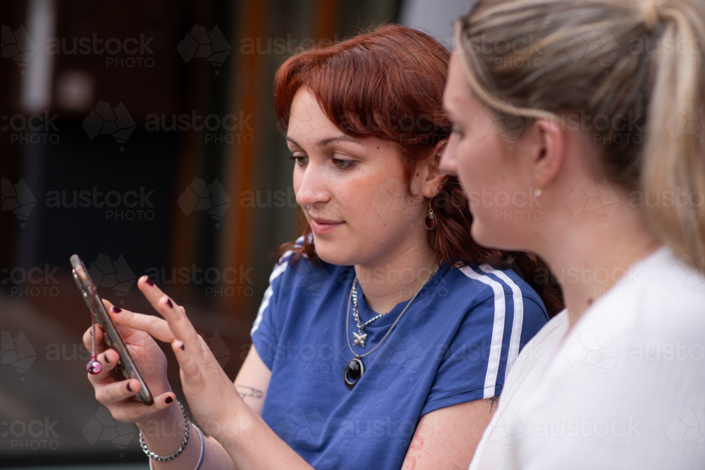 two young women sitting outside at a cafe - Australian Stock Image