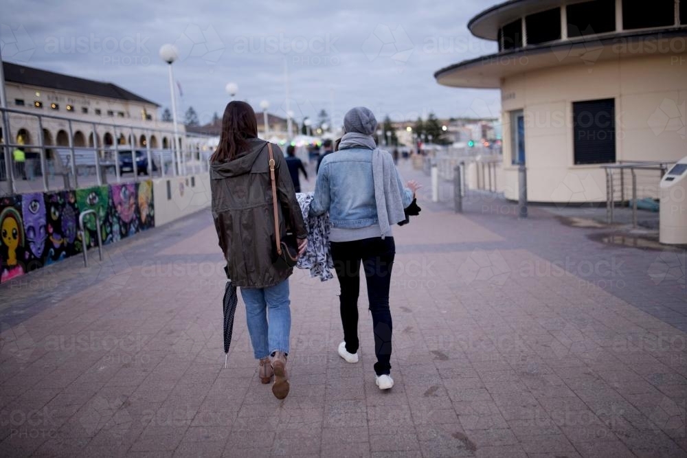 Two young women walking along promenade together - Australian Stock Image
