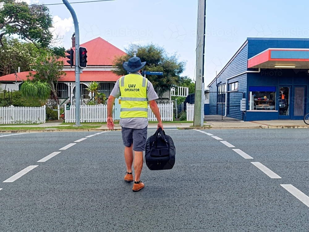 UAV Operator, man walking across the street with a drone in his bag - Australian Stock Image