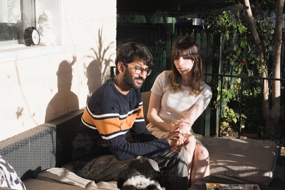 UGC style, couple sitting outside in the sun on their house veranda - Australian Stock Image