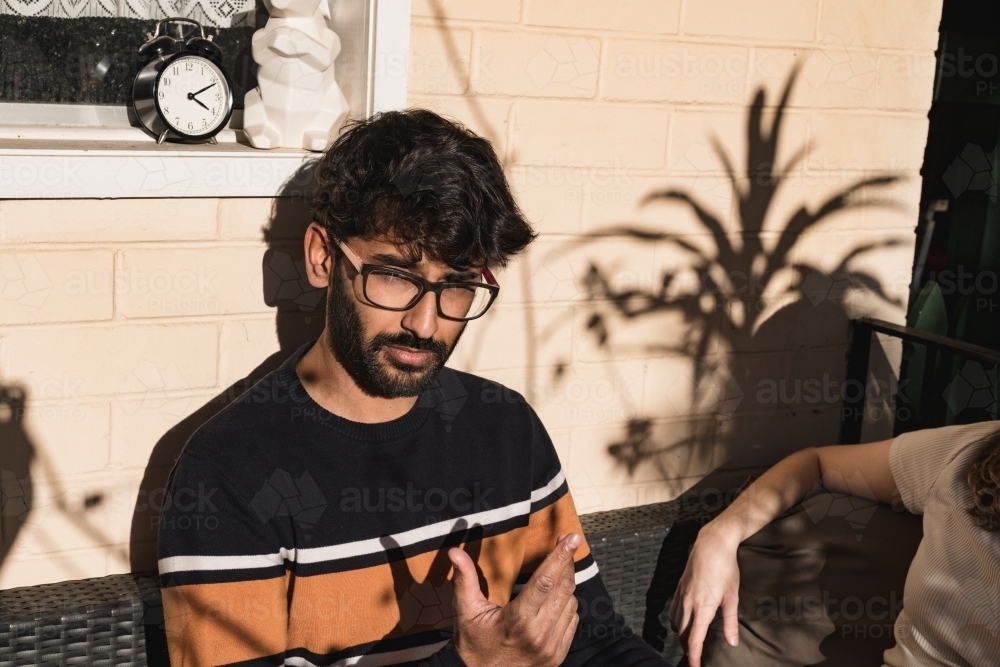 UGC style, couple sitting outside in the sun on their house veranda - Australian Stock Image