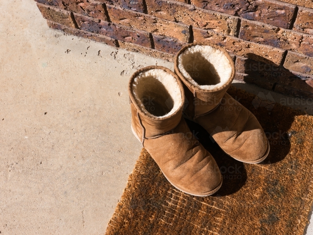 Ugg boots on a worn brown front door mat - Australian Stock Image
