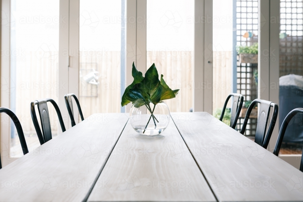 Uncluttered light bright contemporary dining room table with glass doors background - Australian Stock Image