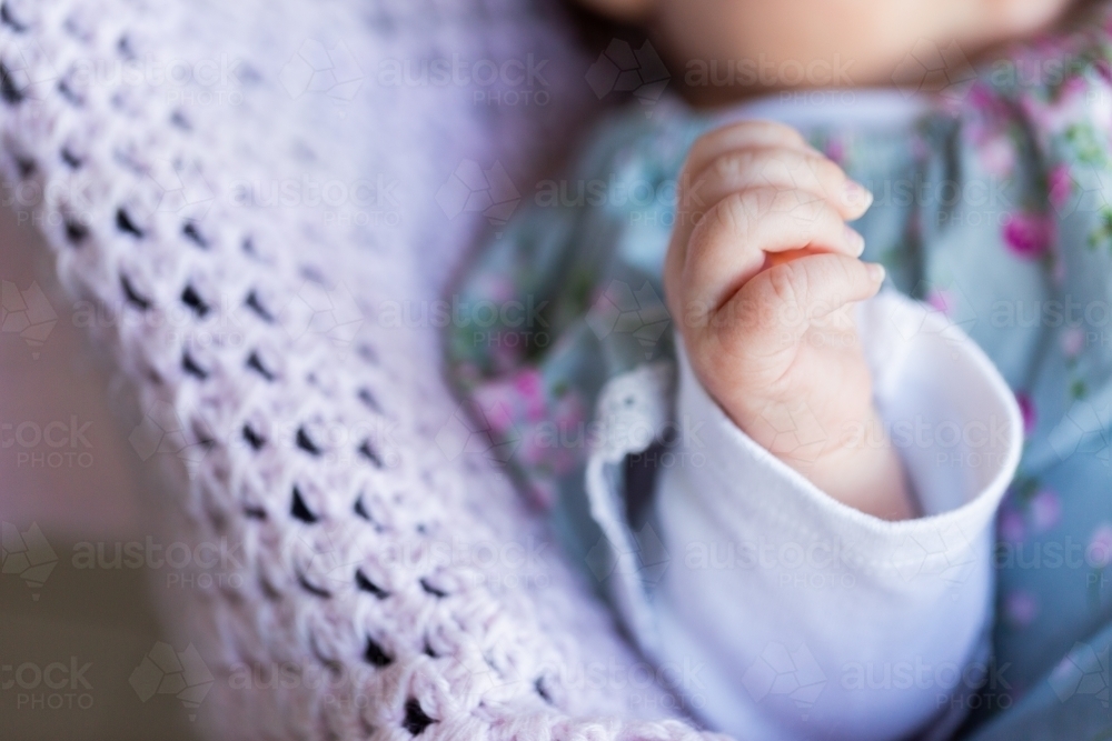 uncurling fingers of newborn baby girl and crochet blanket detail - Australian Stock Image