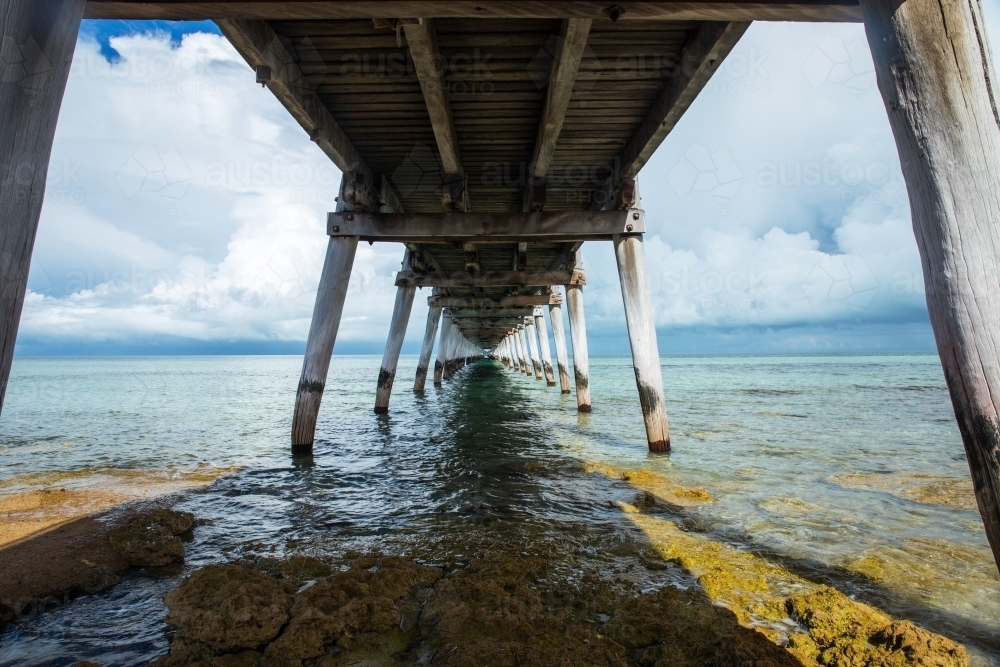 underneath jetty with storm clouds on horizon - Australian Stock Image