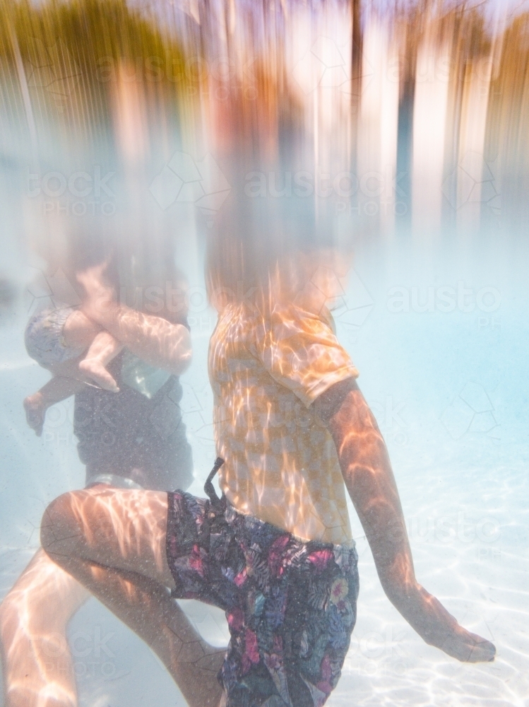 Image of Underwater image of Australian family swimming together in pool in summer Austockphoto