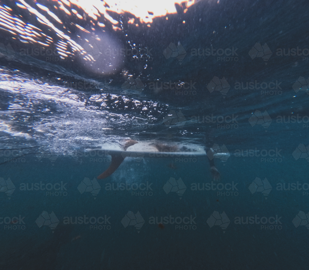 Underwater of females legs sitting on longboard single fin surfboard with good visibility - Australian Stock Image