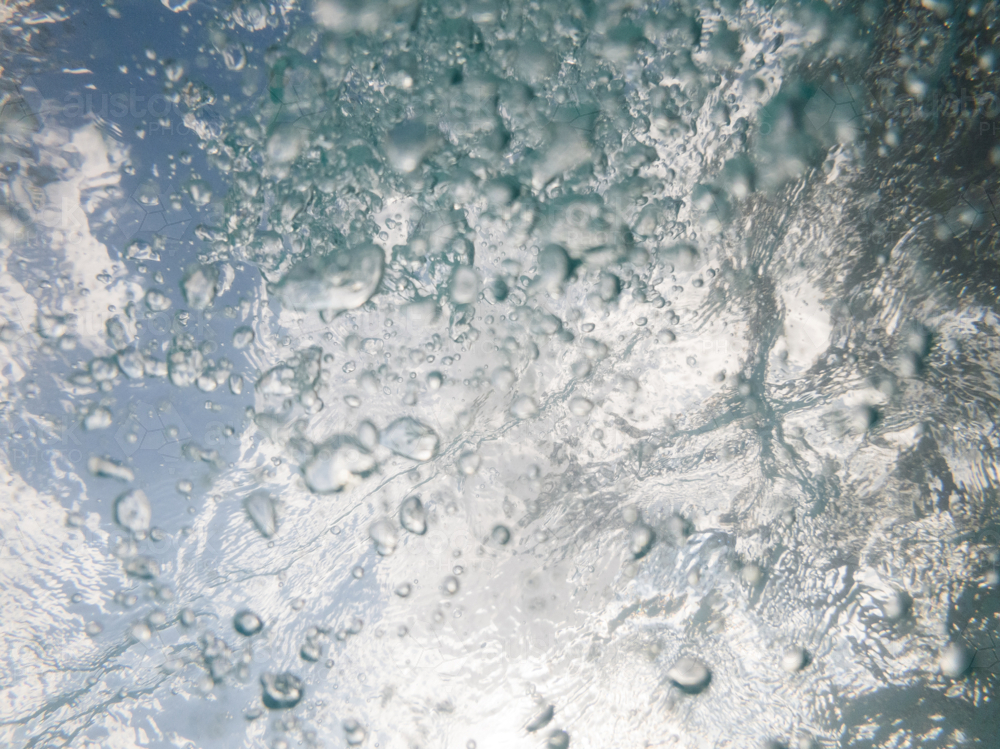 Underwater shot looking up towards the surface through water ripples and bubbles - Australian Stock Image