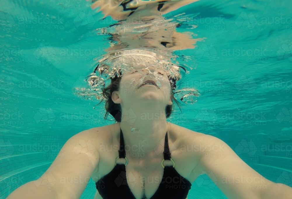 Underwater view of a woman taking a selfie in a swimming pool - Australian Stock Image