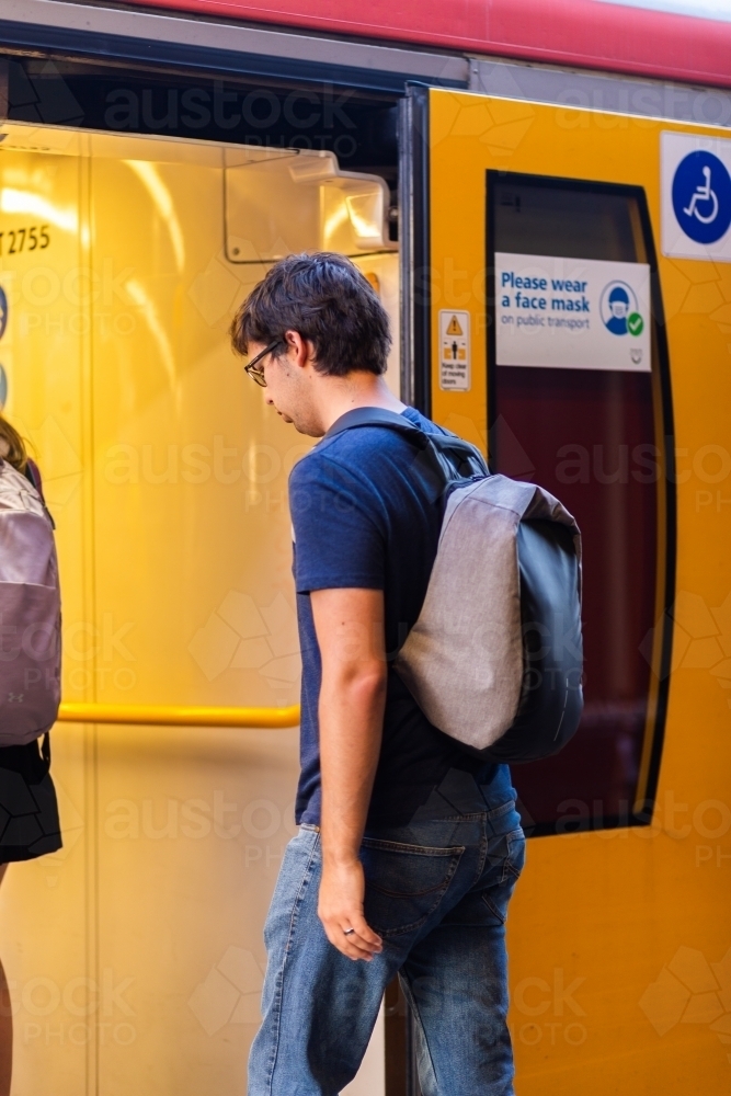 Uni student walking onto train to commute to uni campus - Australian Stock Image