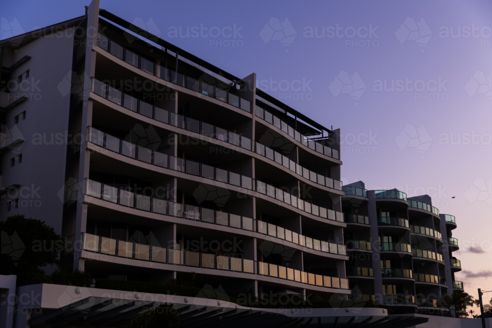 unit blocks with glass balconies reflecting light at dusk - Australian Stock Image