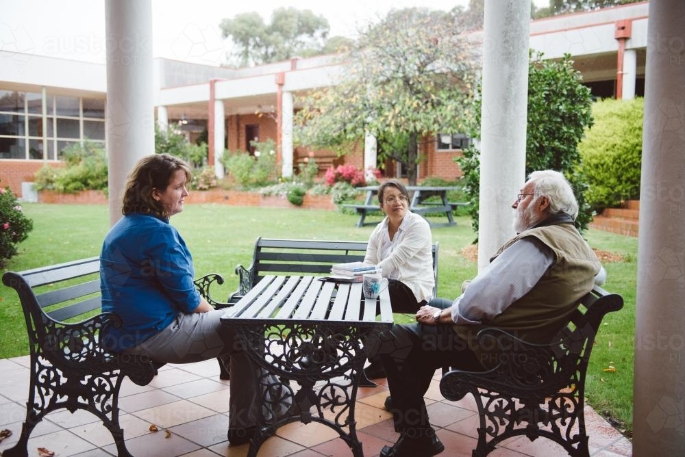 University teachers having a discussion at a bench in the garden - Australian Stock Image