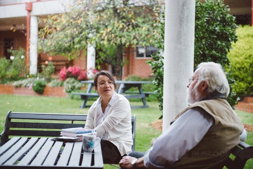 University teachers having a discussion at a bench in the garden - Australian Stock Image