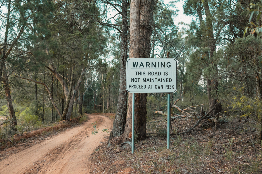 Unmaintained road warning sign in the Australian bush - Australian Stock Image