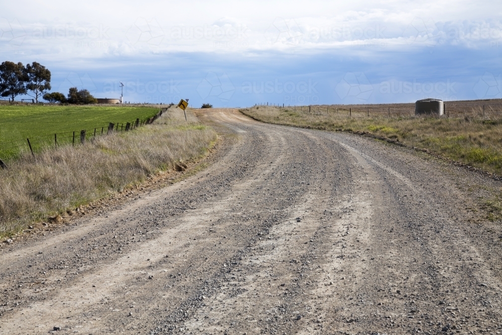 Image of Unsealed dirt road winding up a hill - Austockphoto