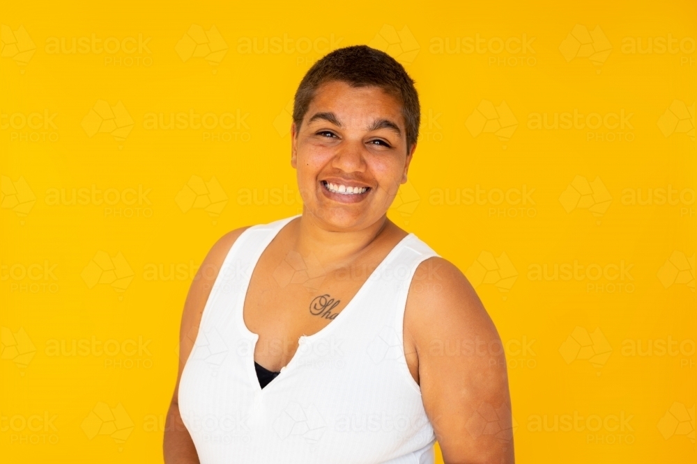 upper body of smiling woman on bright yellow background - Australian Stock Image