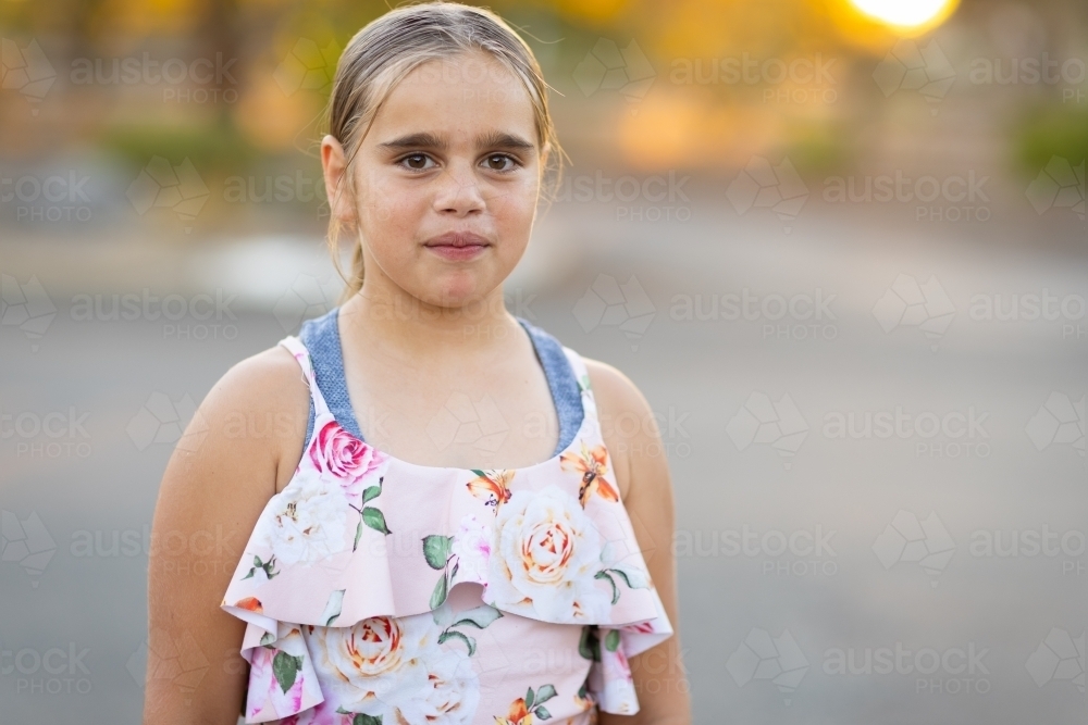 upper body view of young girl standing by herself looking at the camera - Australian Stock Image