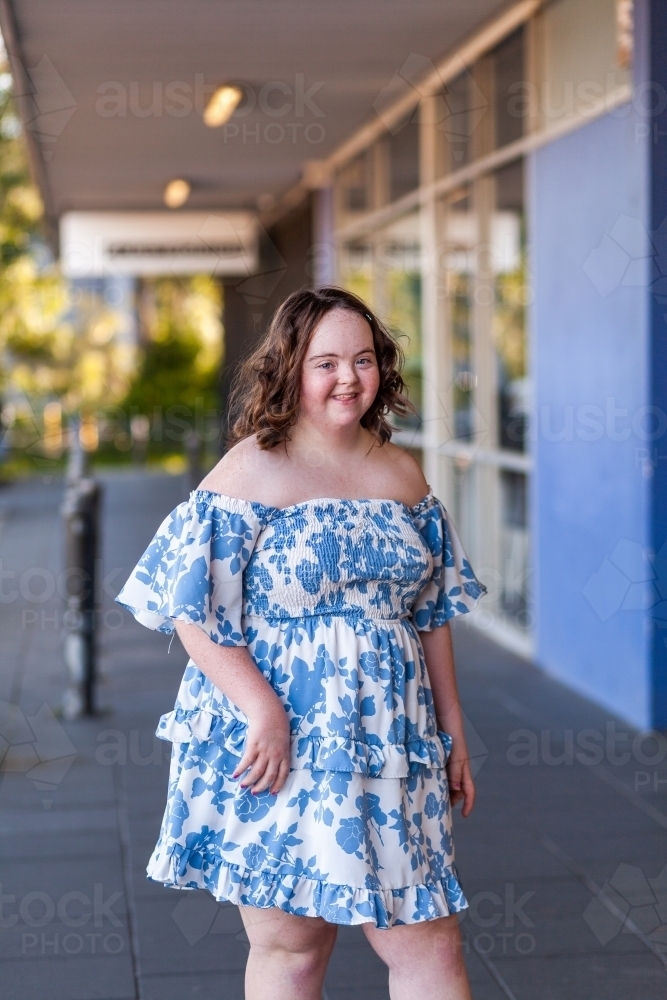Urban portrait of smiling young lady with down syndrome outside shopping centre - Australian Stock Image
