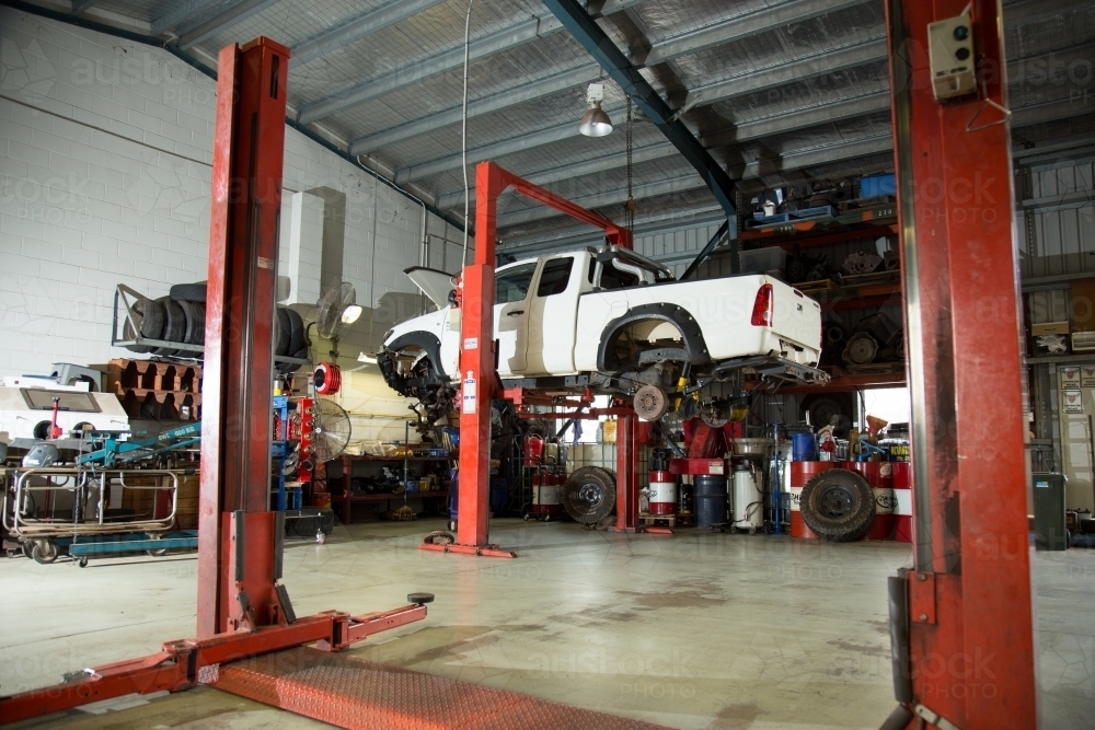 Ute lifted in hoist for repairs in a mechanic workshop - Australian Stock Image