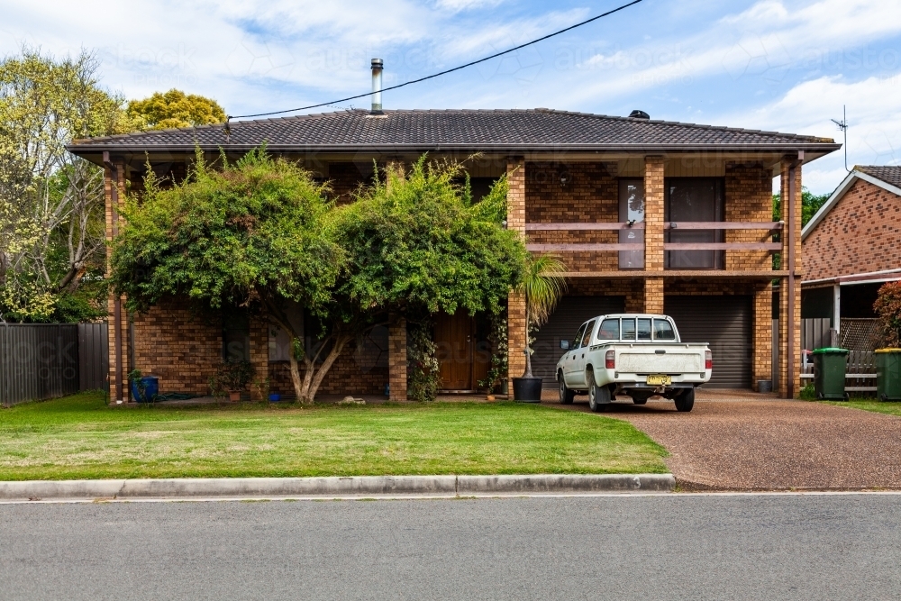 Ute parked in driveway of two story brick home - Australian Stock Image