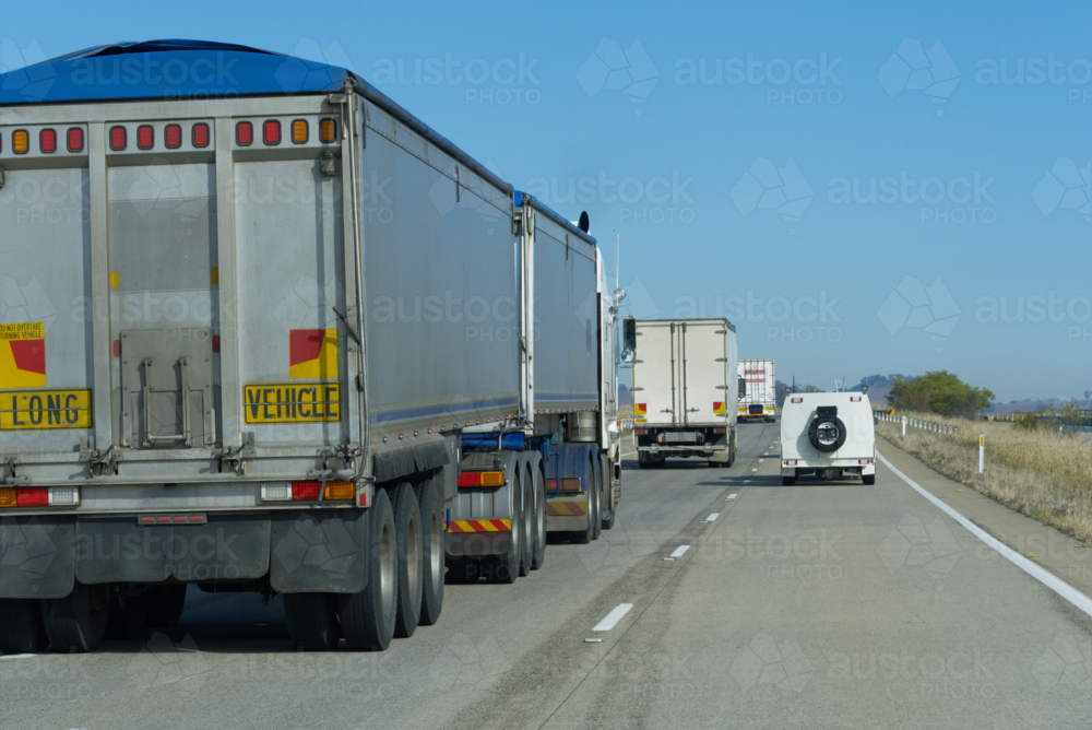 Utility overtaking long trucks on a sunny day - Australian Stock Image