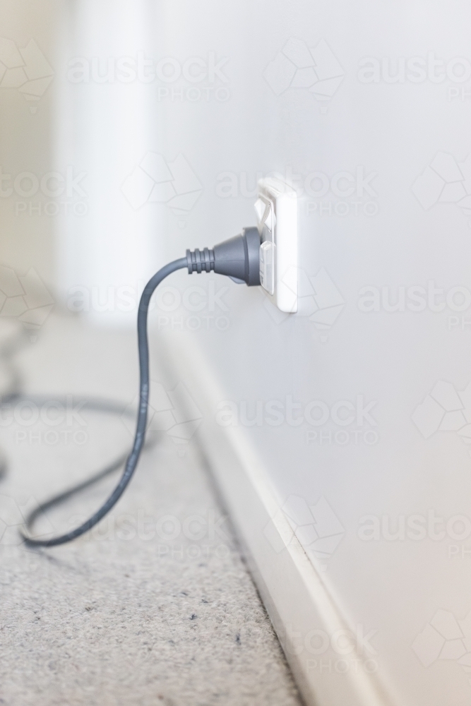 Vacuum cleaner plugged into a power point with child cover over the second one - Australian Stock Image