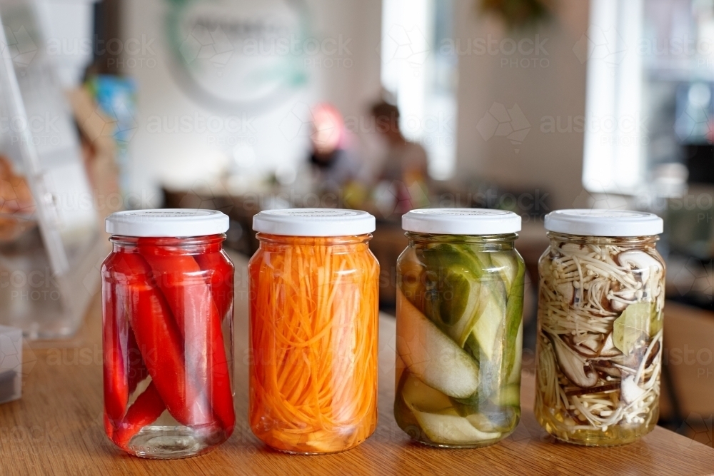 Variety of pickle jars lined up on counter in cafe - Australian Stock Image