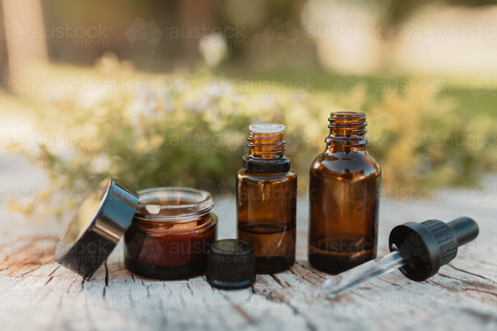 Various amber essential oil bottles in natural outdoor setting - Australian Stock Image