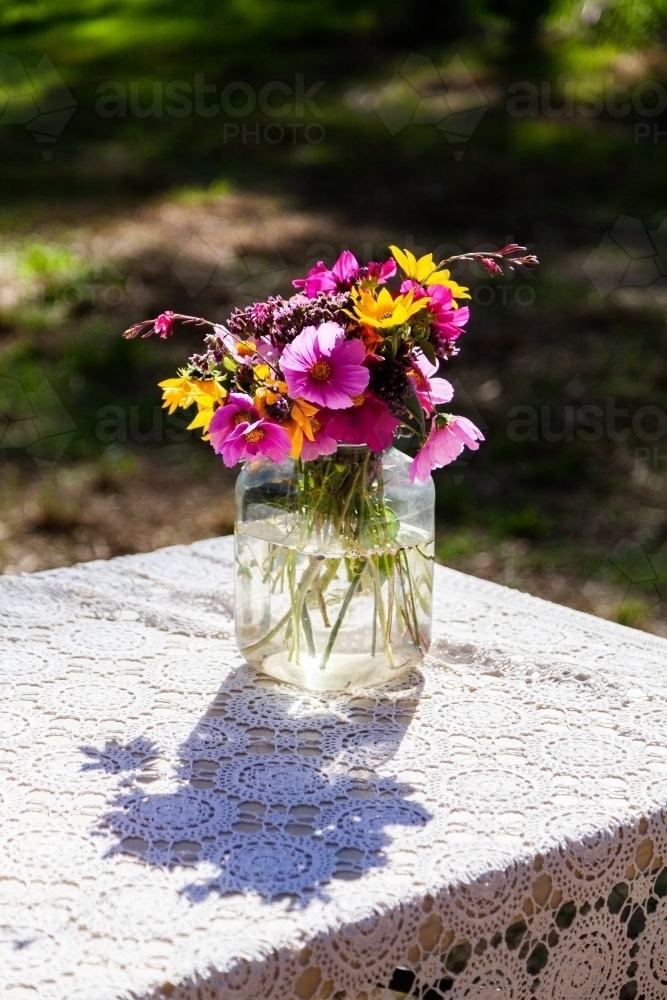 Vase of colourful flowers on table outside ready for a party - Australian Stock Image