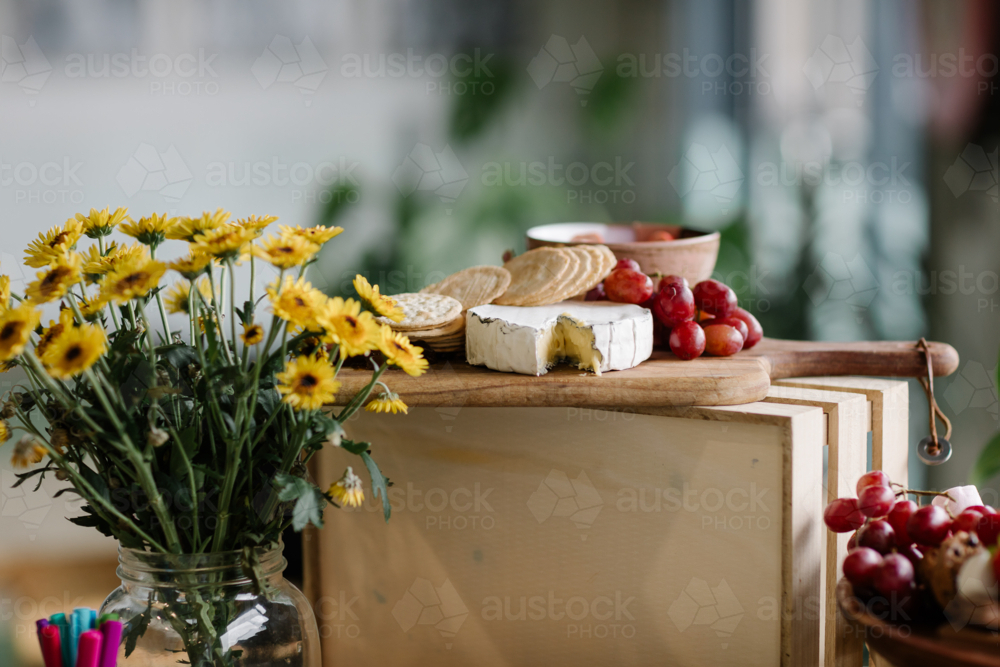 Vase of flowers and cheese platter on table - Australian Stock Image