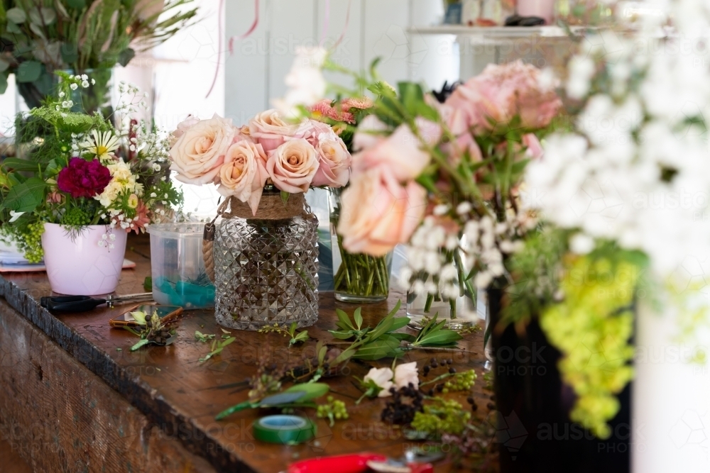 Vases of beautiful pink roses and other flowers with selective focus - Australian Stock Image