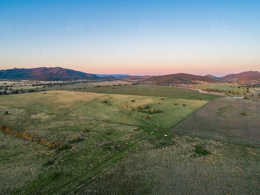 Vast australian pastoral landscape at dusk with clear sky and hills on horizon - Australian Stock Image