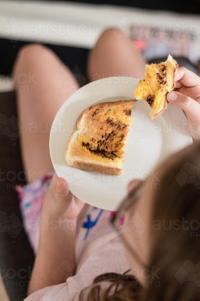 vegemite toast on a plate on a girl's lap - Australian Stock Image