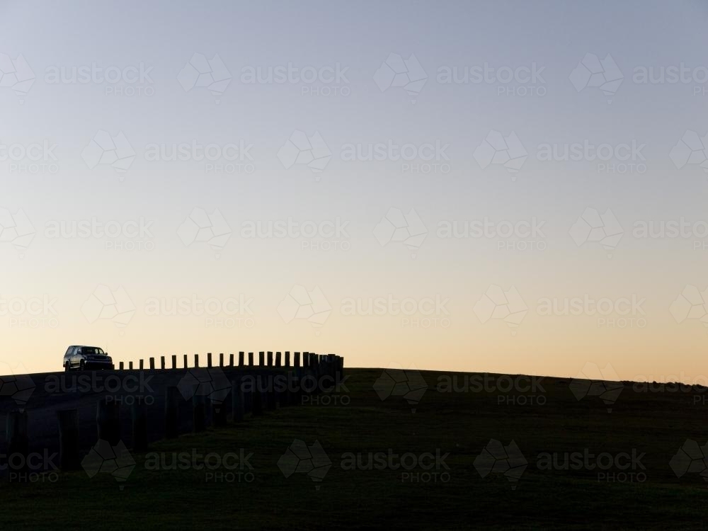 Vehicle and posts silhouetted against evening sky - Australian Stock Image