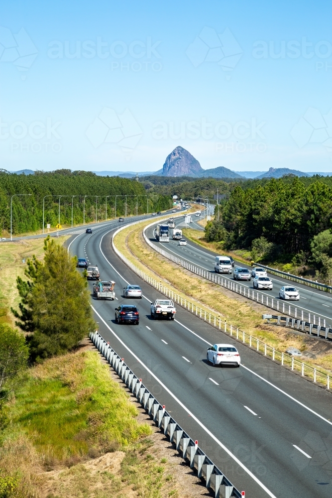 Vehicles driving the M1 Bruce Highway with glass house mountains in background. - Australian Stock Image