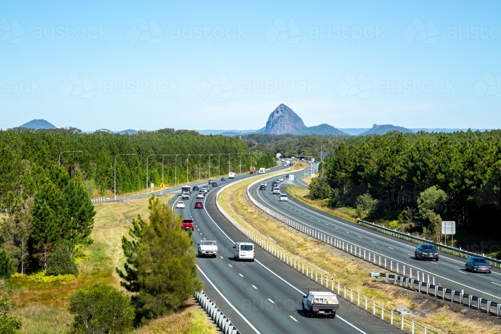 Vehicles driving the M1 Bruce Highway with glass house mountains in background. - Australian Stock Image