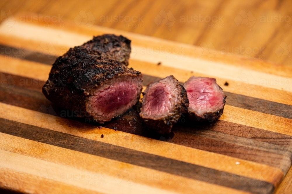 Venison cooked and cut on a timber chopping board - Australian Stock Image