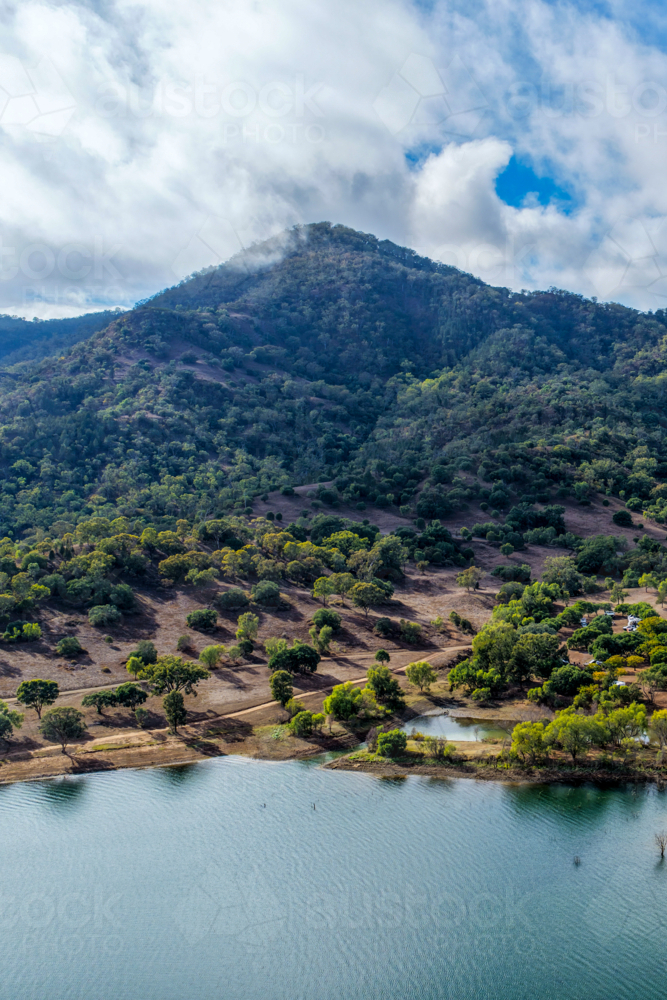 Vertical Aerial view of the Glenbawn Dam shoreline with a cloudy sky over the surrounding mountains - Australian Stock Image